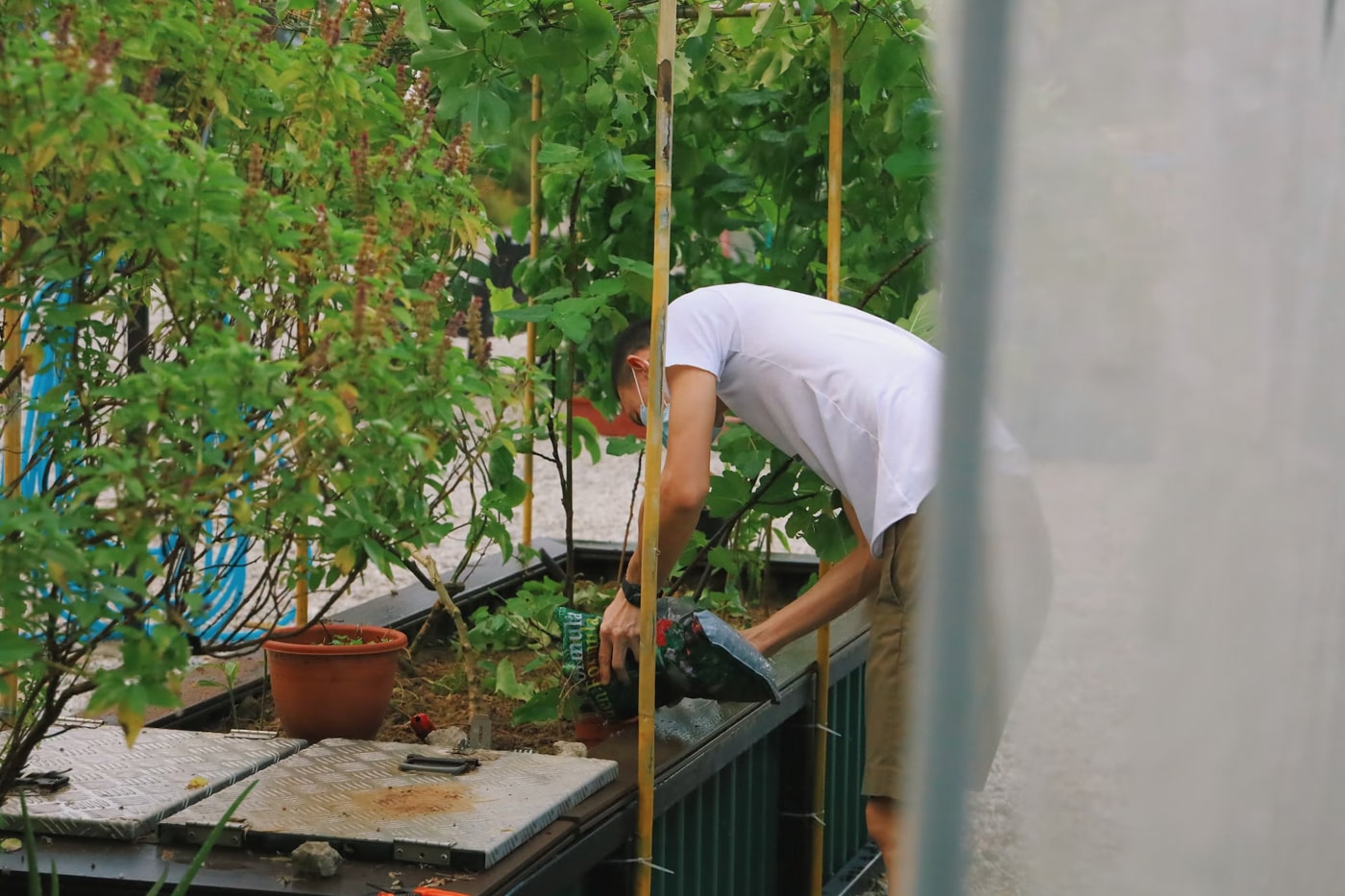 man putting soil on his backyard raised bed garden